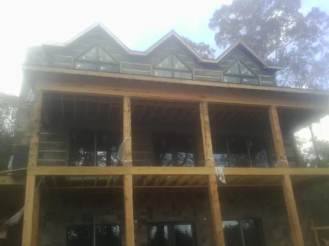 Dormers and porch framing on a large log home under construction — Roof Coating work by our crew in Red Hill