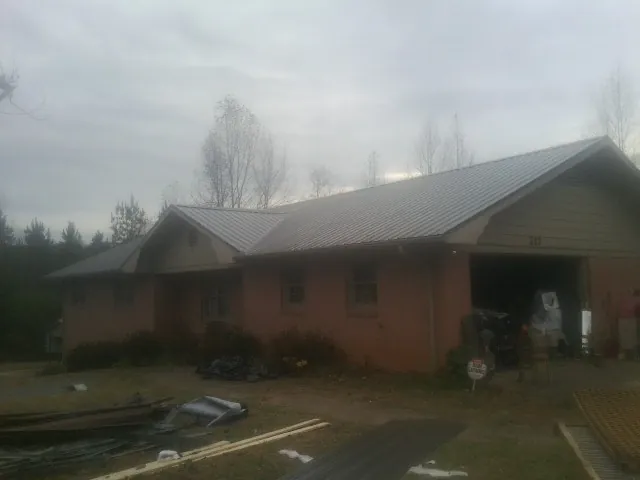 Gray metal roof on a stucco house with an attached garage in Red Hill