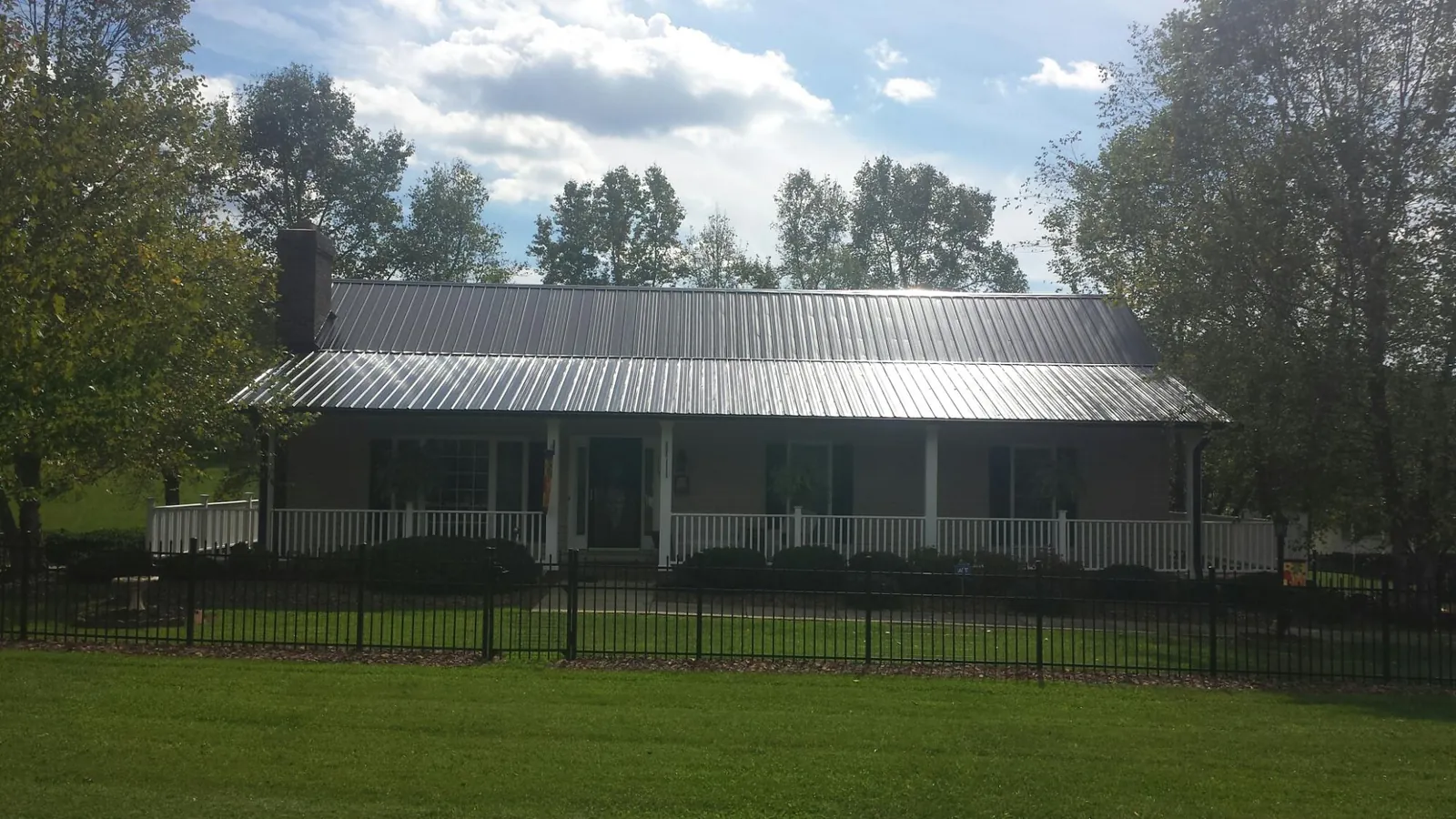 Gray metal roof on a brick ranch with a full width front porch — Gutter Guard Installation work by our crew in Red Hill